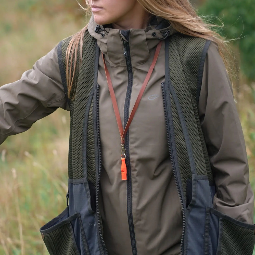 Miljöbild tjej på fält med acme pro trialler 212 neon orange med junies visselpipsband läder cognac #color_neon-orange